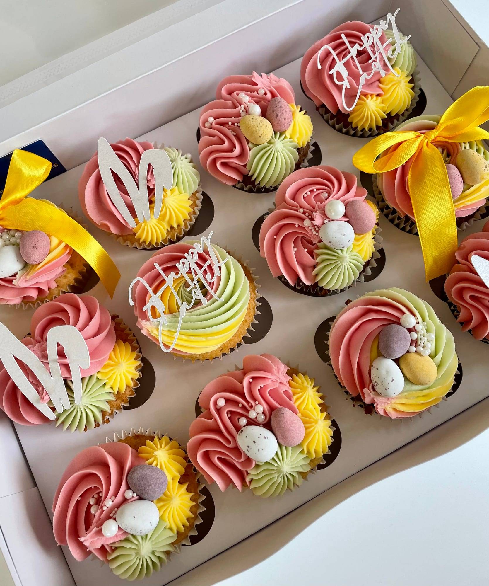 Easter cupcakes with pink, yellow and green swirled buttercream, mini chocolate eggs and bunny ear toppers