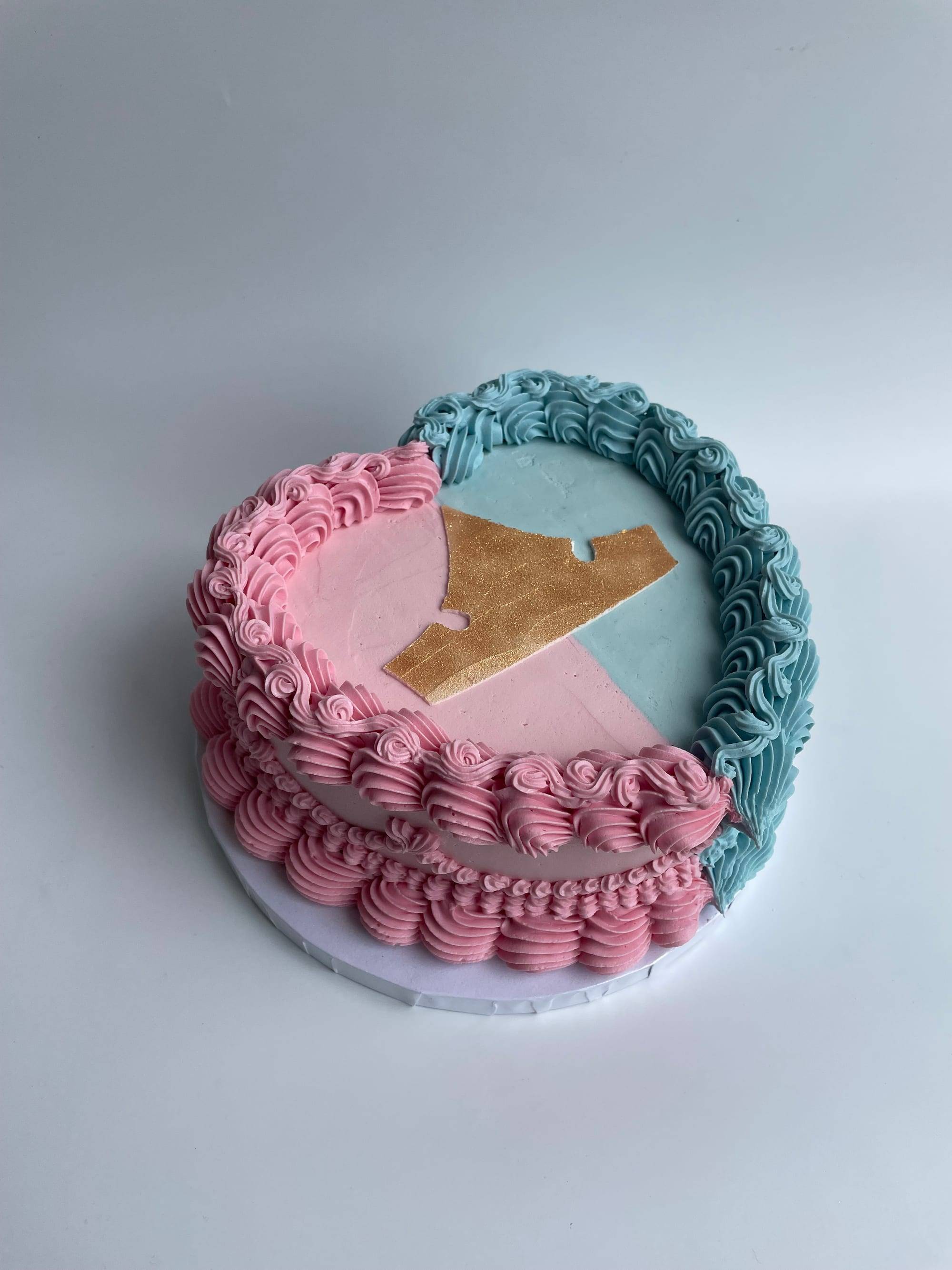 Heart-shaped two-tone cake in pink and dusty blue buttercream with a gold fondant accent