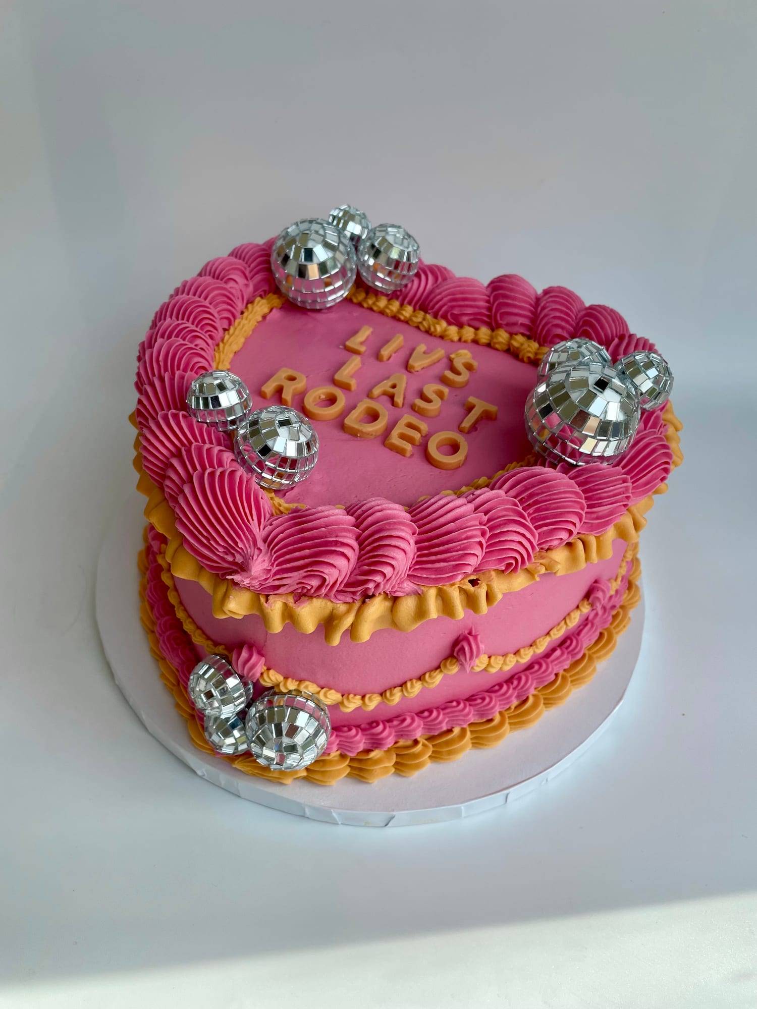 Heart-shaped hen party cake in hot pink and mustard buttercream with disco ball decorations